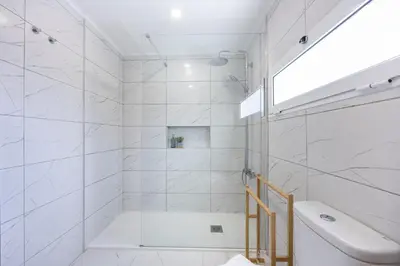 a white bathroom with a shower and a sink at Alfamar Beach Apartment in Albufeira