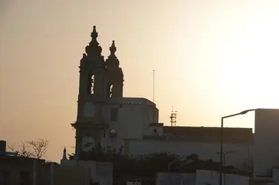 a silhouette of a building with a clock tower at Blue House - City's Heart in Faro
