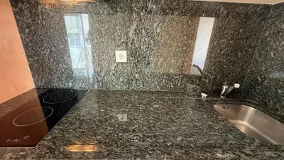 a bathroom with a granite counter top and a sink at Apartamento T1 Pau da Bandeira in Caliços