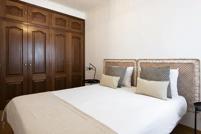 a bedroom with a large white bed with wooden cabinets at Mango 2 - Faro City Center by HD in Faro