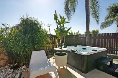 a backyard with a hot tub and a table and chairs at Sunshine Villa em Vilamoura in Vilamoura