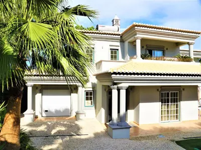 a white house with a palm tree in front of it at Exceptional villa with swimming pool in Almancil