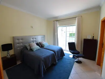a bedroom with a bed and a chair and a window at Exceptional villa with swimming pool in Almancil