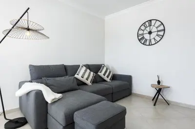 a living room with a couch and a clock on the wall at Golfinho - Sea view with pool by HD in Quarteira