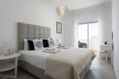 a white bedroom with a large bed and a window at Golfinho - Sea view with pool by HD in Quarteira