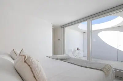 a white bedroom with a large window at Espuma do Tempo in Quarteira