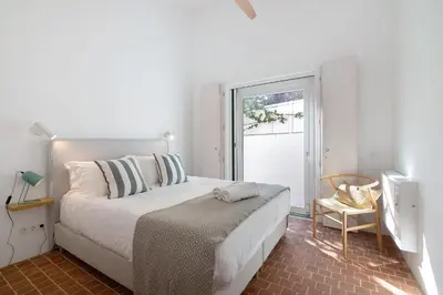 a white bedroom with a bed and a window at Espuma do Tempo in Quarteira