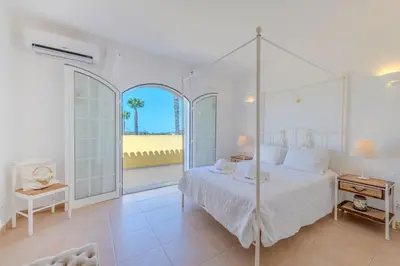 a white bedroom with a bed and a large window at Villa Monte da Torre in Loulé