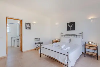 a bedroom with a bed and a table and a bathroom at Villa Monte da Torre in Loulé