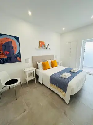 a white bedroom with a bed and a chair at Casa Eliz Modern Comfort in the center of Faro in Faro