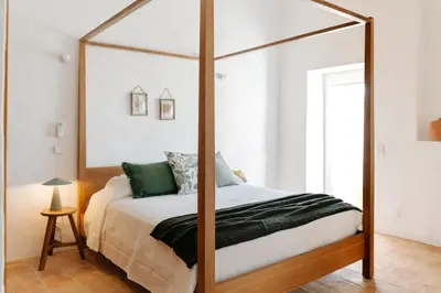 a bedroom with a canopy bed with a wooden frame at Casa Majú - Algarve in Valados