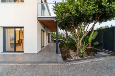an external view of a house with a tree at Stylish Algarve Retreat- Priv. Pool & Beach Nearby in Quarteira