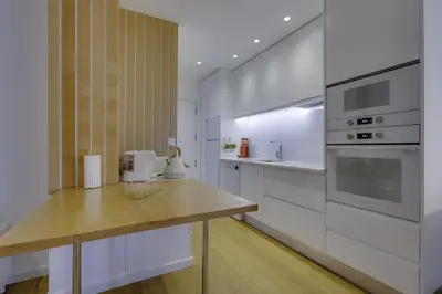 a kitchen with white cabinets and a wooden counter top at GINGKO BILOBA ROOF TOP by My Algarve Rentals in Quarteira