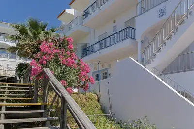 a white building with stairs and pink flowers at Casa João Bravo in Albufeira