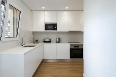 a kitchen with white cabinets and a sink and a window at Mira Mar 1 - Near the beach by HD in Quarteira