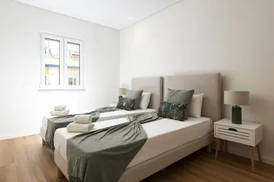 a white bedroom with two beds and a window at Mira Mar 2 - Near the beach by HD in Quarteira