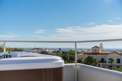 a balcony with a tub and a view of a building at New Villa - Rooftop Jacuzzi & Sunset Views in Santa Bárbara de Nexe