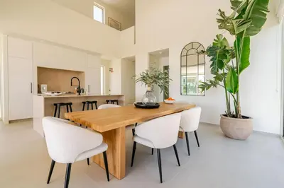 a dining room with a wooden table and white chairs at New Villa - Rooftop Jacuzzi & Sunset Views in Santa Bárbara de Nexe