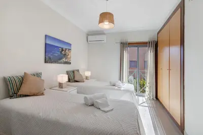 a white bedroom with two beds and a window at Do Vale Hollidays in Guia