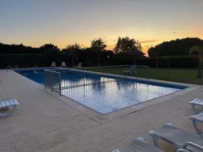 a swimming pool with chairs and a sunset in the background at Do Vale Hollidays in Guia