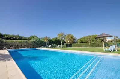 a blue swimming pool with an umbrella next to a yard at Do Vale Hollidays in Guia