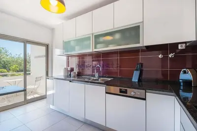 a kitchen with white cabinets and a large window at Galé by the Sea in Guia