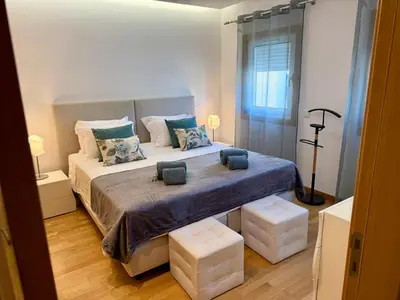 a bedroom with a large bed with two ottomans at Apartamento Flor de Amendoeira Garden in Albufeira