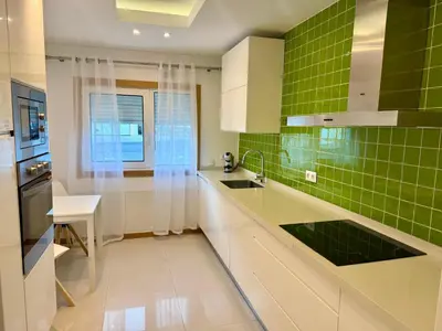 a kitchen with green tiled walls and white cabinets at Apartamento Flor de Amendoeira Garden in Albufeira