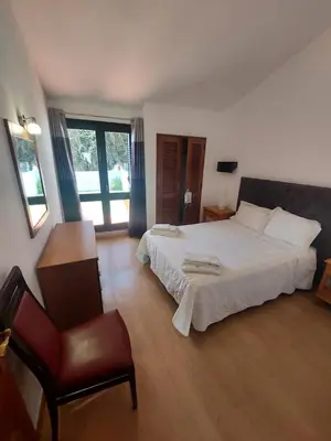 a bedroom with a large white bed and a chair at Jacaranda 43-Moradia terrea in Albufeira