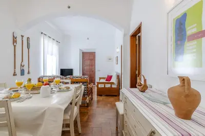 a dining room with white tables and chairs and a vase at #341 Casa da Guida 44 by Home Holidays in Olhos de Água