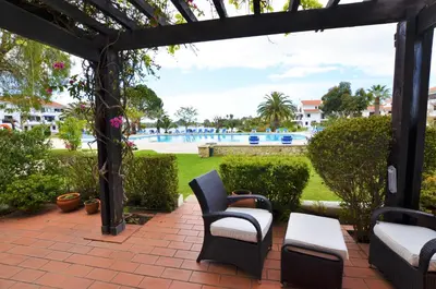 a patio with chairs and a pool in the background at Apartamento Mariana, Quinta do Lago