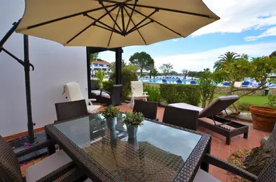 a patio with a glass table and an umbrella at Apartamento Mariana, Quinta do Lago