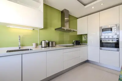 a kitchen with white cabinets and green walls at #340 Old Town Garden Hill Z by Home Holidays in Albufeira