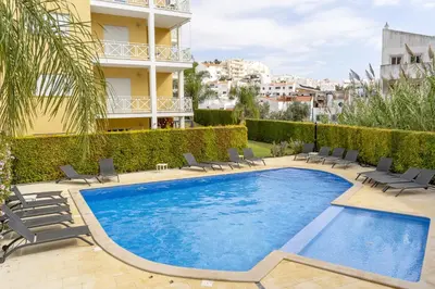 a swimming pool with chairs and a building at #340 Old Town Garden Hill Z by Home Holidays in Albufeira
