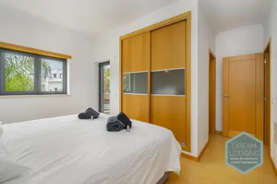 a bedroom with a large white bed and a wooden cabinet at Quinta do Pinheiro Residence AF - Dream Lodging in Albufeira