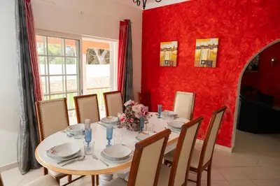 a dining room with a table and a red wall at Vila Paraiso da Maria 5 quartos duas salas, jardim, piscina, varanda com churrasqueira e WIFI in Olhos de Água
