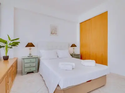 a bedroom with a large white bed with two night stands at Apartamento Mourasuites, T1 moderno em Vilamoura in Quarteira
