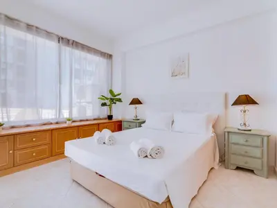 a bedroom with a large white bed with two towels at Apartamento Mourasuites, T1 moderno em Vilamoura in Quarteira