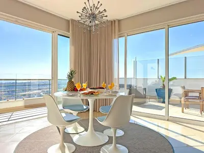 a dining room with a table and chairs and large windows at Serenity by the Ocean Penthouse by BeCherish in Páteo