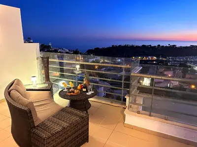 a table with fruit on a balcony with the sunset at Serenity by the Ocean Penthouse by BeCherish in Páteo