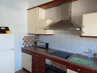 a kitchen with wooden cabinets and a counter top at EncostaOasis Townhouse in Estibeira