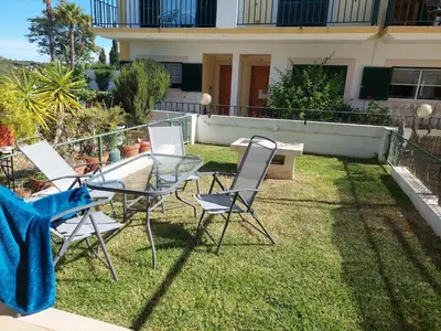 a group of chairs and a glass table in a yard at EncostaOasis Townhouse in Estibeira