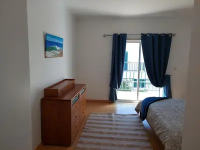 a bedroom with a bed and a dresser and a window at EncostaOasis Townhouse in Estibeira