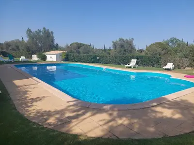 a large pool with blue water in a yard at EncostaOasis Townhouse in Estibeira