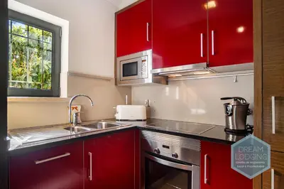 a kitchen with red cabinets and a sink at Pinheiro Residence - Dream Lodging in Albufeira