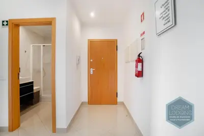 a hallway with a fire extinguisher sign and a door at Pinheiro Residence - Dream Lodging in Albufeira