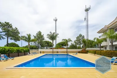 a swimming pool in a resort with chairs and trees at Pinheiro Residence - Dream Lodging in Albufeira