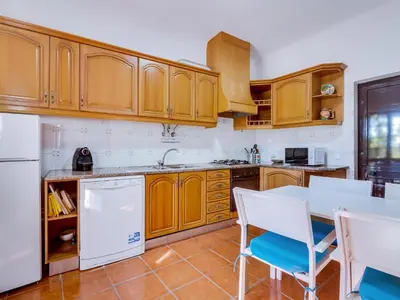 a kitchen with wooden cabinets and a white refrigerator at Vivenda Pereiras com 2 quartos em Quarteira in Quarteira