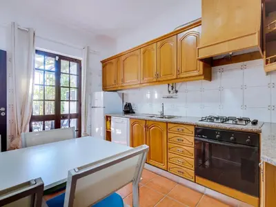 a kitchen with wooden cabinets and a white refrigerator at Vivenda Pereiras com 2 quartos em Quarteira in Quarteira