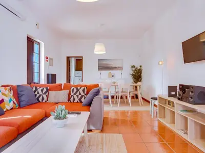 a living room with an orange couch and a table at Vivenda Pereiras com 2 quartos em Quarteira in Quarteira
